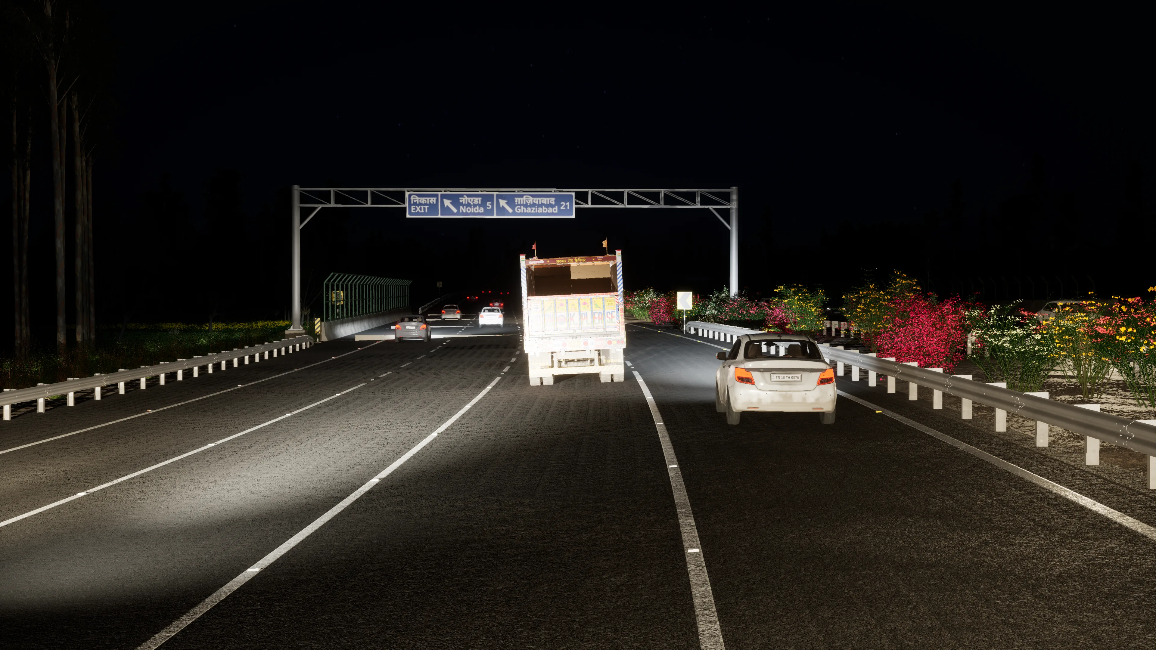 An expressway at night lit only by headlights, a gantry sign for Noida and Ghaziabad ahead